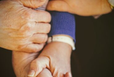 person in blue long sleeve shirt holding babys hand