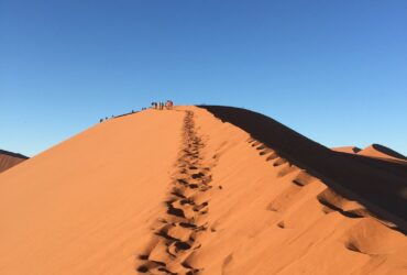 photo of foot prints on desert hill during daytime