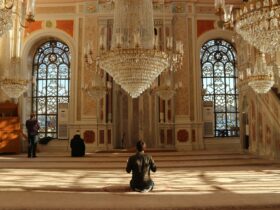 man in black jacket sitting on brown concrete floor