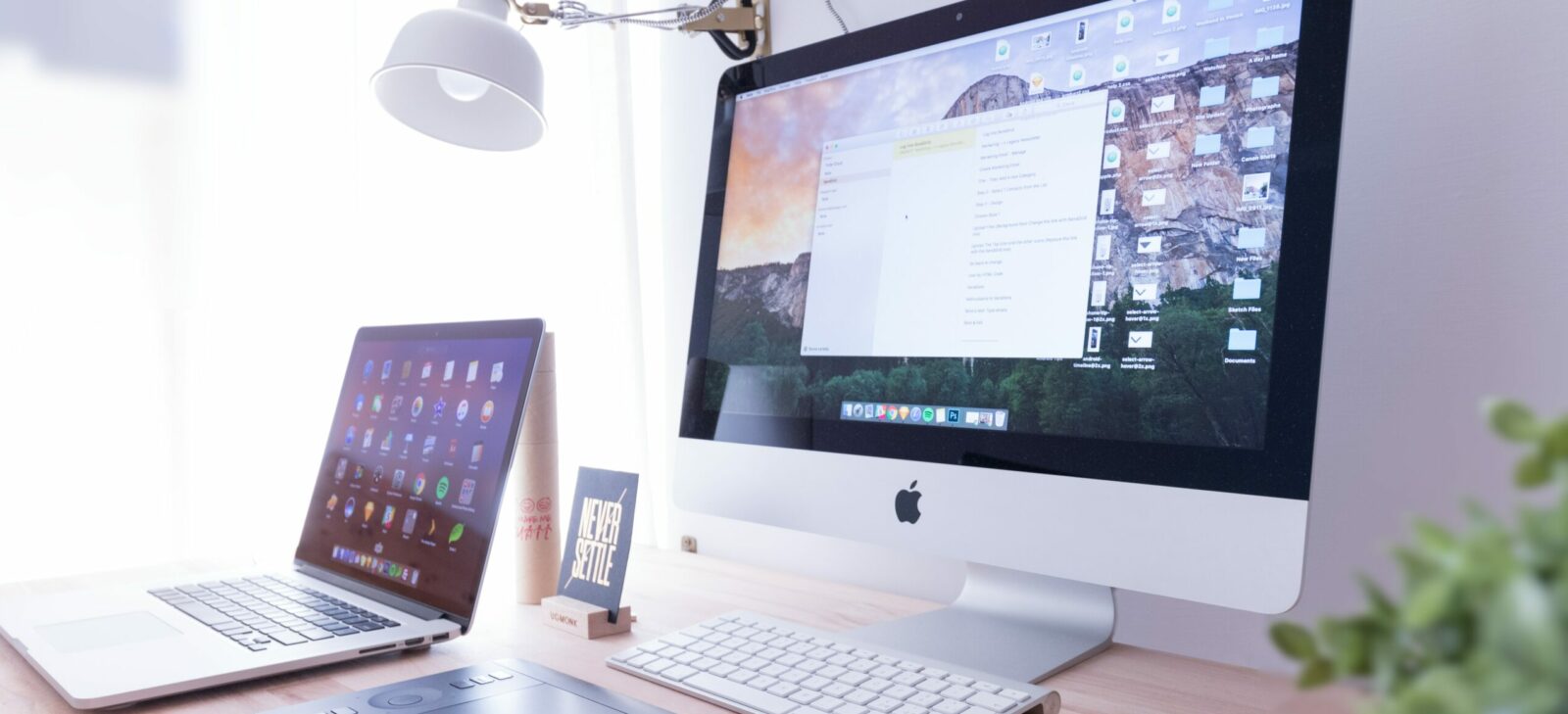 silver iMac near iPhone on brown wooden table