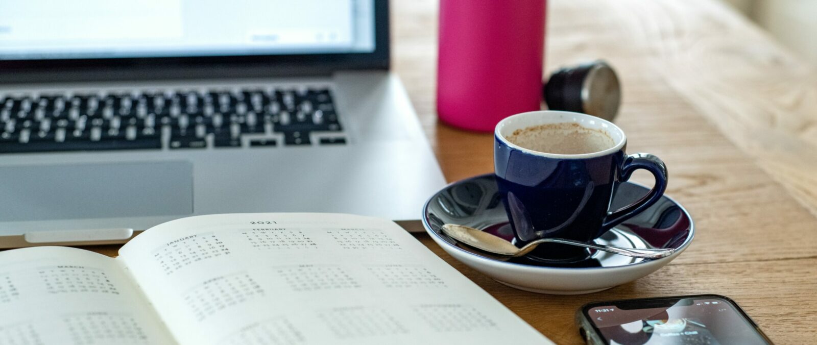 black and white ceramic mug on saucer beside macbook pro