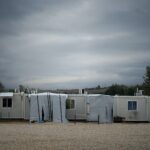 white and gray camper trailer on green grass field under gray cloudy sky during daytime