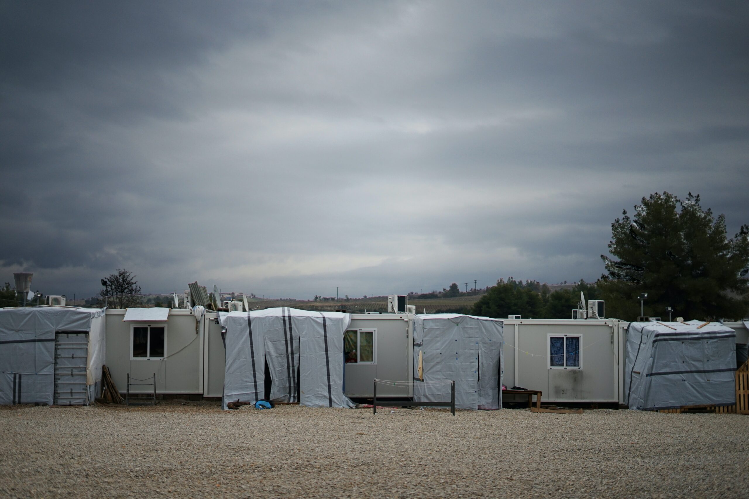 white and gray camper trailer on green grass field under gray cloudy sky during daytime