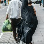 woman in black dress holding green plastic bag