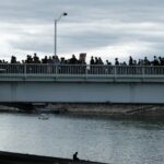 people walking on bridge over river during daytime