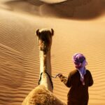 person walking beside camel