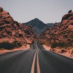 black concrete road surrounded by brown rocks
