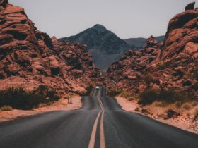 black concrete road surrounded by brown rocks