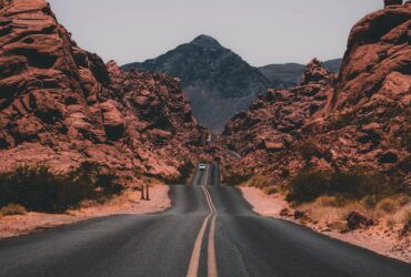 black concrete road surrounded by brown rocks