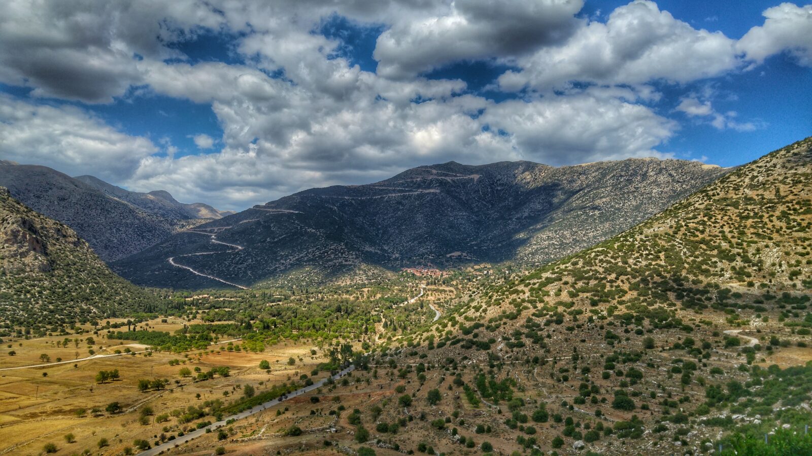 green grass field and mountains under white clouds and blue sky during daytime