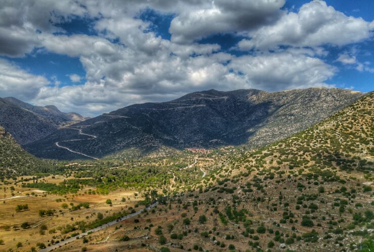 green grass field and mountains under white clouds and blue sky during daytime