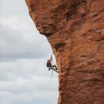man in black shorts climbing brown rock formation during daytime