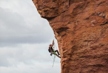 man in black shorts climbing brown rock formation during daytime
