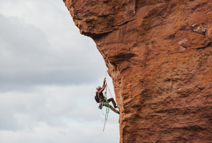 man in black shorts climbing brown rock formation during daytime