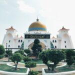 trees in front of white and yellow mosque