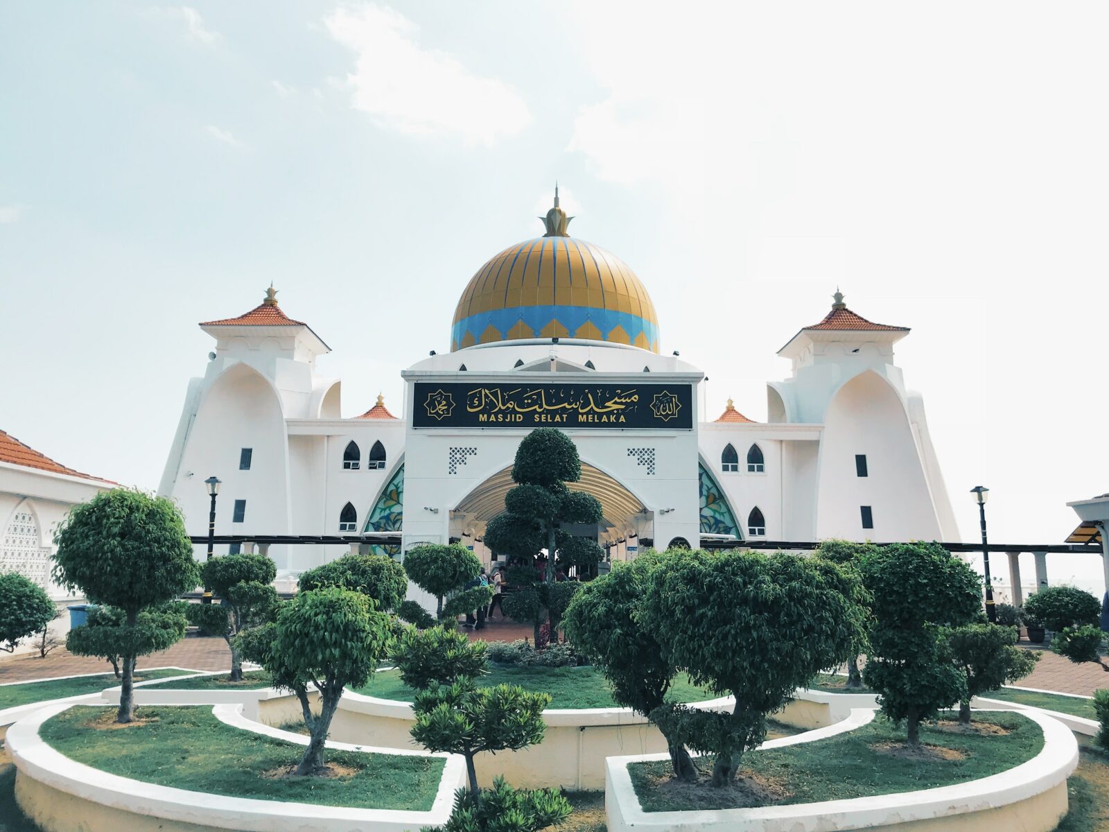 trees in front of white and yellow mosque