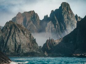 brown rocky mountain beside blue sea under white sky during daytime