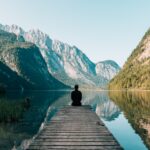 man sitting on gray dock