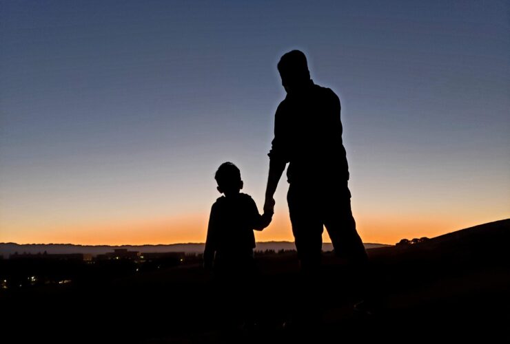silhouette of man and woman standing on beach during sunset