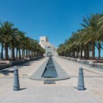white concrete building near palm trees under blue sky during daytime
