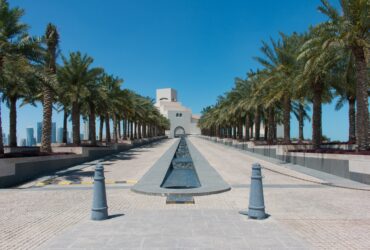 white concrete building near palm trees under blue sky during daytime
