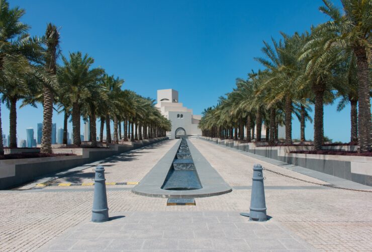 white concrete building near palm trees under blue sky during daytime