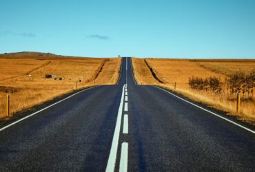 black asphalt road between brown fields during daytime