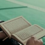 person reading book on green table