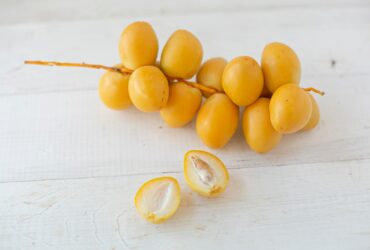yellow round fruits on white wooden table