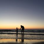 silhouette of man and kid on seashore