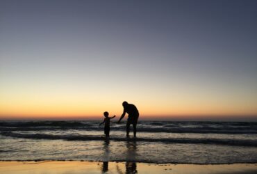 silhouette of man and kid on seashore
