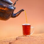 black teapot pouring brown liquid on brown ceramic mug