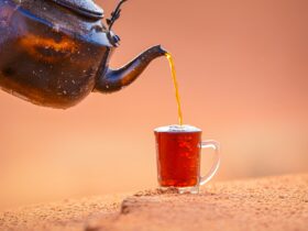 black teapot pouring brown liquid on brown ceramic mug