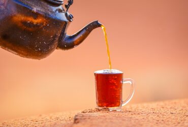 black teapot pouring brown liquid on brown ceramic mug