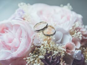 gold-colored bridal ring set on pink rose flower bouquet