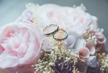 gold-colored bridal ring set on pink rose flower bouquet