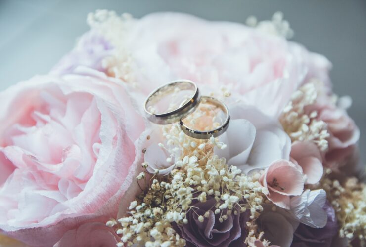 gold-colored bridal ring set on pink rose flower bouquet