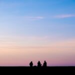 silhouette photography of three person sitting under sky