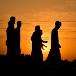 silhouette of 2 women standing on field during sunset