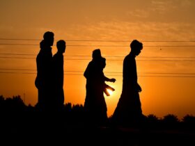 silhouette of 2 women standing on field during sunset