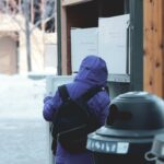 person in blue hoodie and blue denim jeans sitting on black plastic trash bin