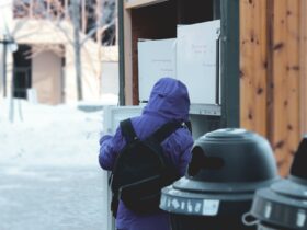 person in blue hoodie and blue denim jeans sitting on black plastic trash bin