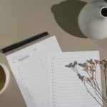 white printer paper beside white ceramic mug