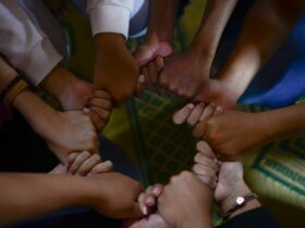 man in white t-shirt holding babys hand