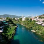 body of water between green trees and buildings under blue sky during daytime