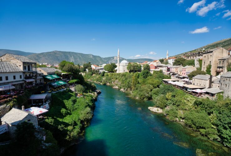 body of water between green trees and buildings under blue sky during daytime
