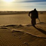 man in black shirt and black pants standing on brown sand during daytime