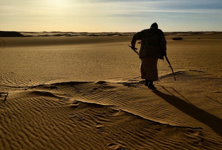 man in black shirt and black pants standing on brown sand during daytime