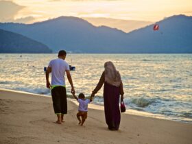 man and woman holding hands while walking on beach during daytime