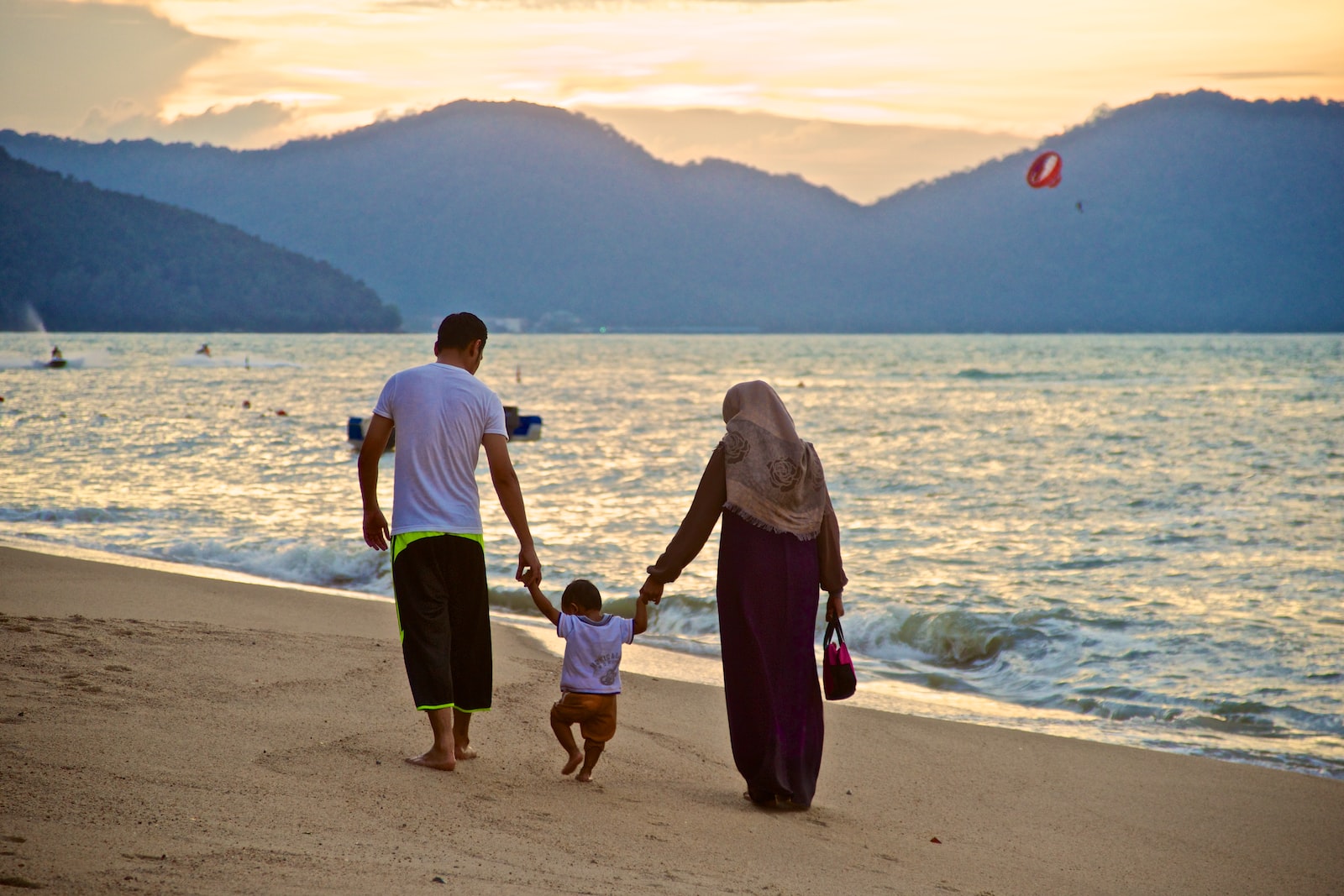 man and woman holding hands while walking on beach during daytime